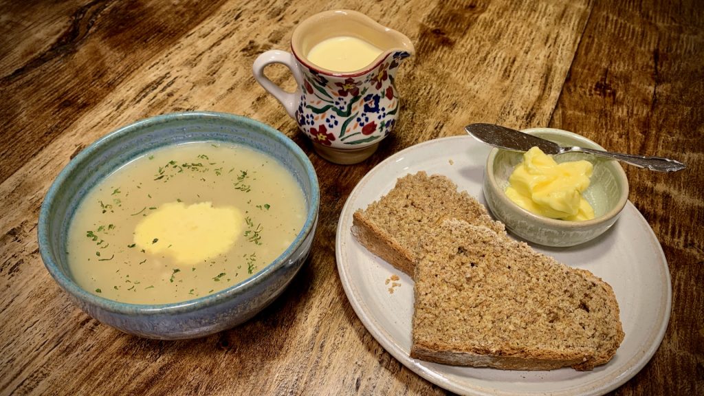 A bowl of Irish potato soup with sliced soda bread and Kerry Gold butter